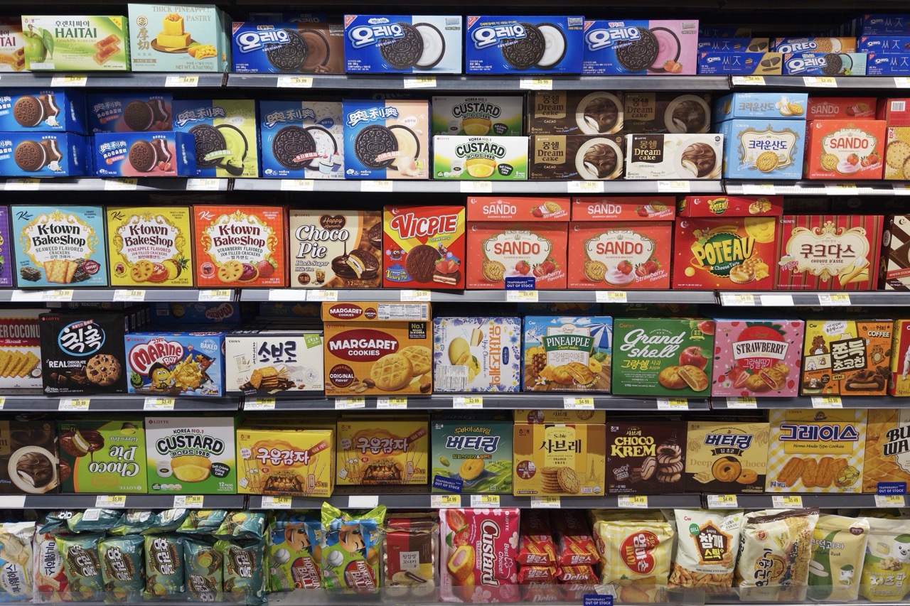 Supermarket shelves packed with boxed cookies and crackers, mostly Korean brands like Oreo, Custard, and K-town BakeShop, price tags lining every shelf edge.