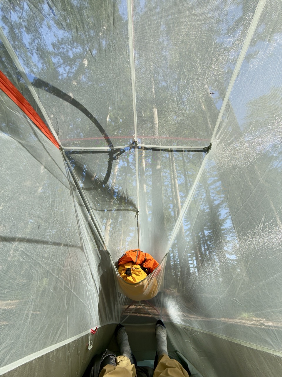The inside view of a one person ultra-light freestanding backpacking tent, with some clothes stashed in the attic.