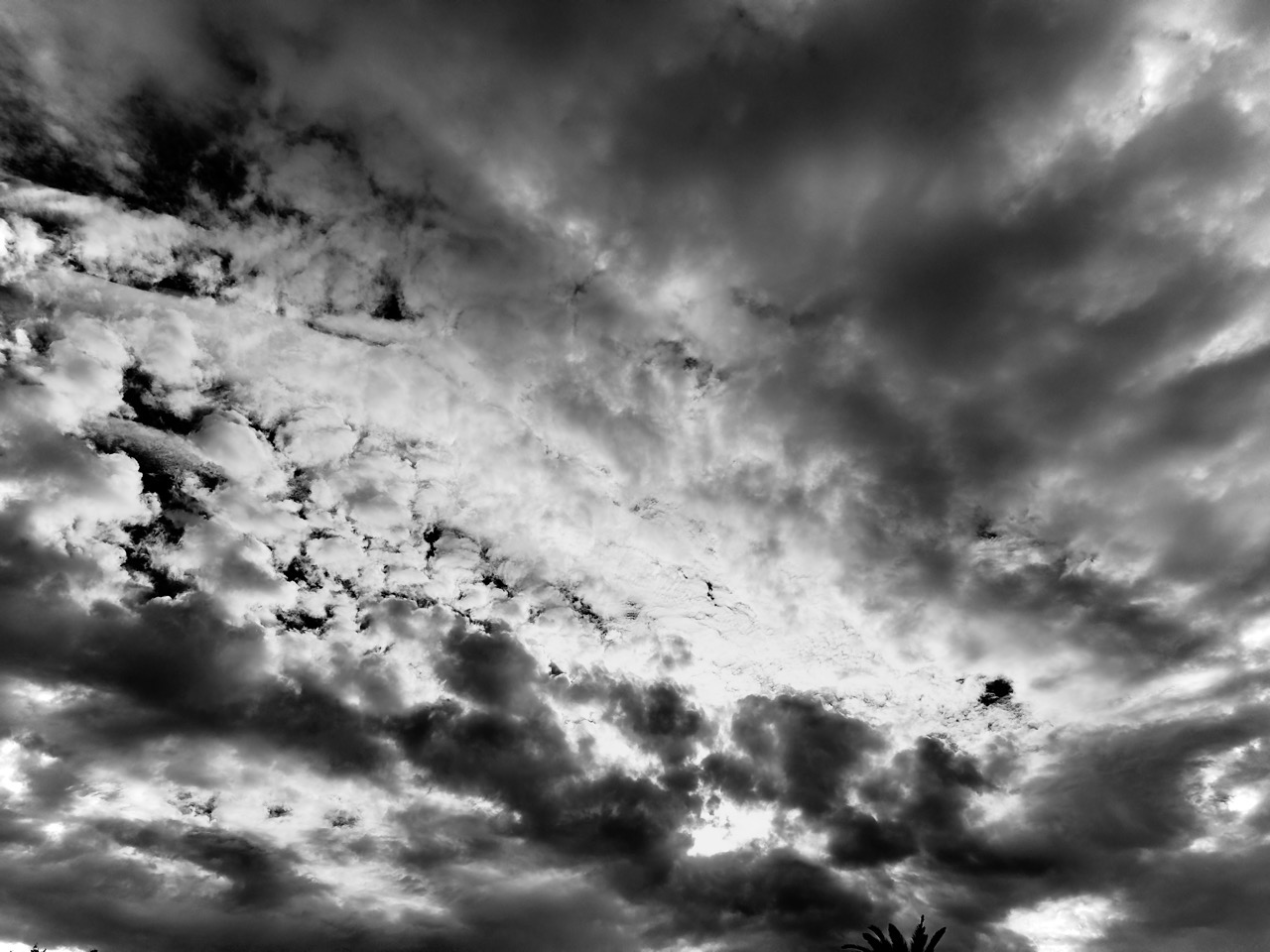 Textured black and white cloud formations filling the sky with contrasting dark clouds and bright patches.