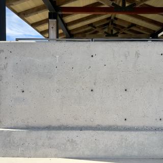 A large concrete pillar beneath a park pavilion's peaked roof, with a tiny stick-figure drawing near its top.