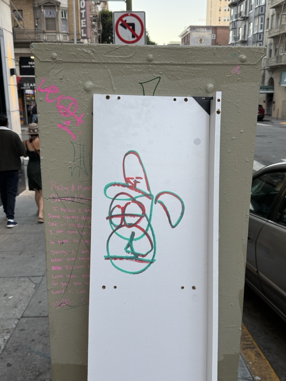 A utility box covered in graffiti, with a red and green scribble drawn on a white panel