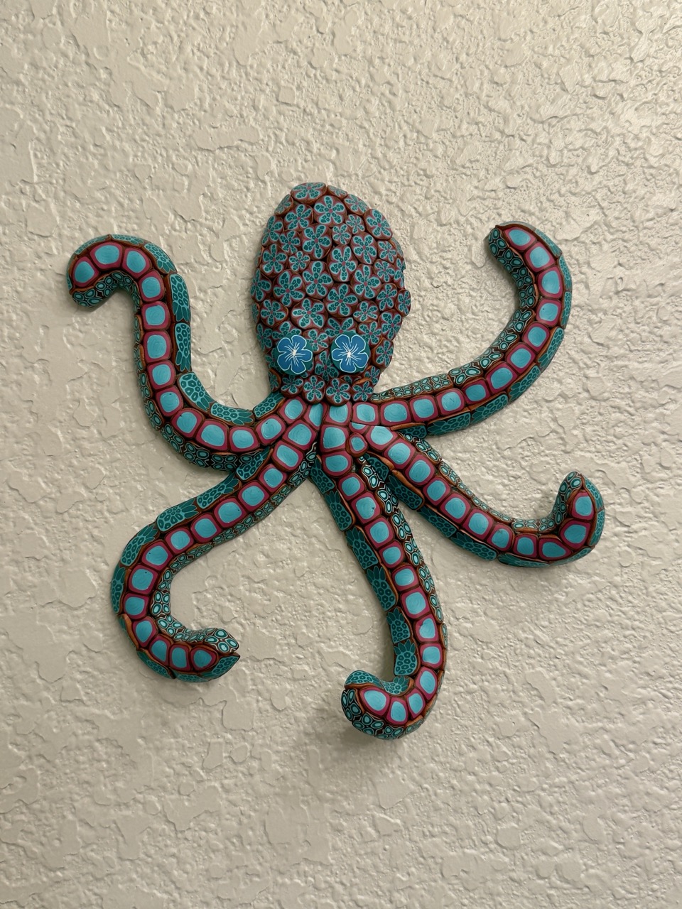 A colorful polymer-clay octopus sculpture mounted on a textured wall