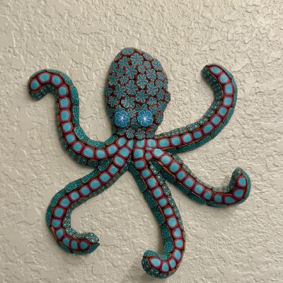 A colorful polymer-clay octopus sculpture mounted on a textured wall