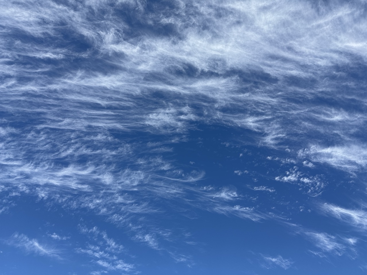 Wispy cirrus clouds streaking across a blue sky