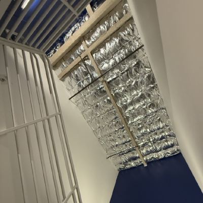 Looking up a narrow stairwell to a ceiling of exposed silver duct insulation, a wall below reading "Physical activity will add years to your life, and life to your years."
