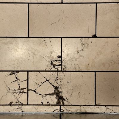 A floor of cream marble tiles laced with dark natural veining and fine cracks.