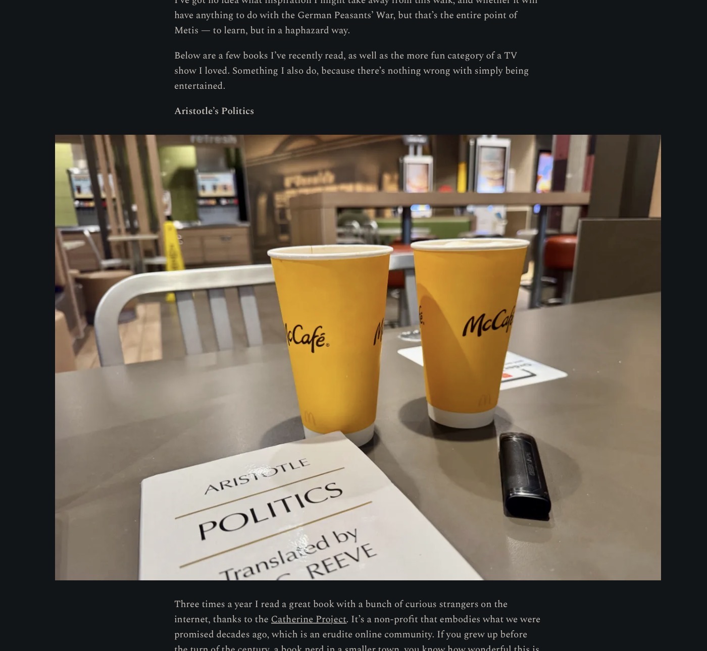 It is the interior of a McDonalds, on the table in front of the camera are two yellow paper coffee cups and a paperback copy of Aristotle’s Politics