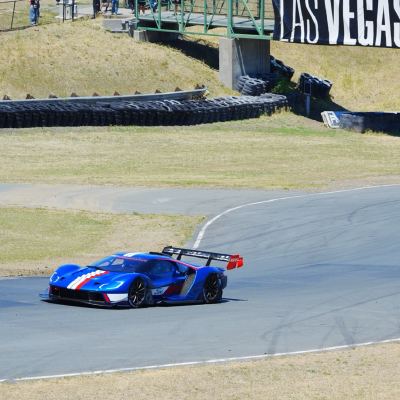 A blue Ford GT leading a second through a sweeping turn, Las Vegas and Sunoco banners behind.