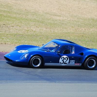 A blue vintage GT coupe, number 32, turning through a corner.