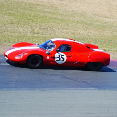 A red vintage coupe with a white stripe, number 35, cornering.